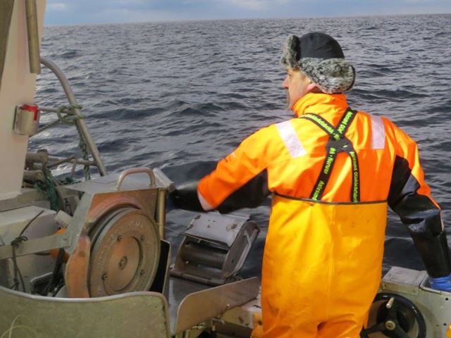 Bilde av fisker i gult oljehyre på linebåt.
