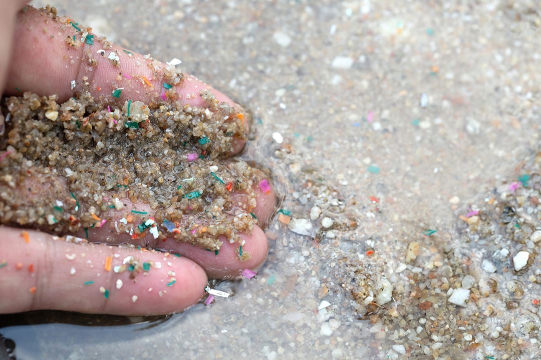 Sand og mikroplast i hånd på strand