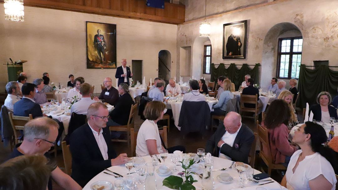 A group of people at a conference dinner, in a medieval hall.