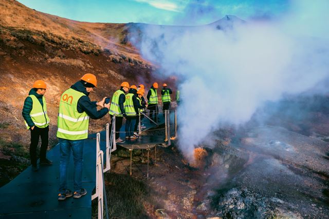 En gruppe mennesker observerer en jordvarmebrønn på Island.